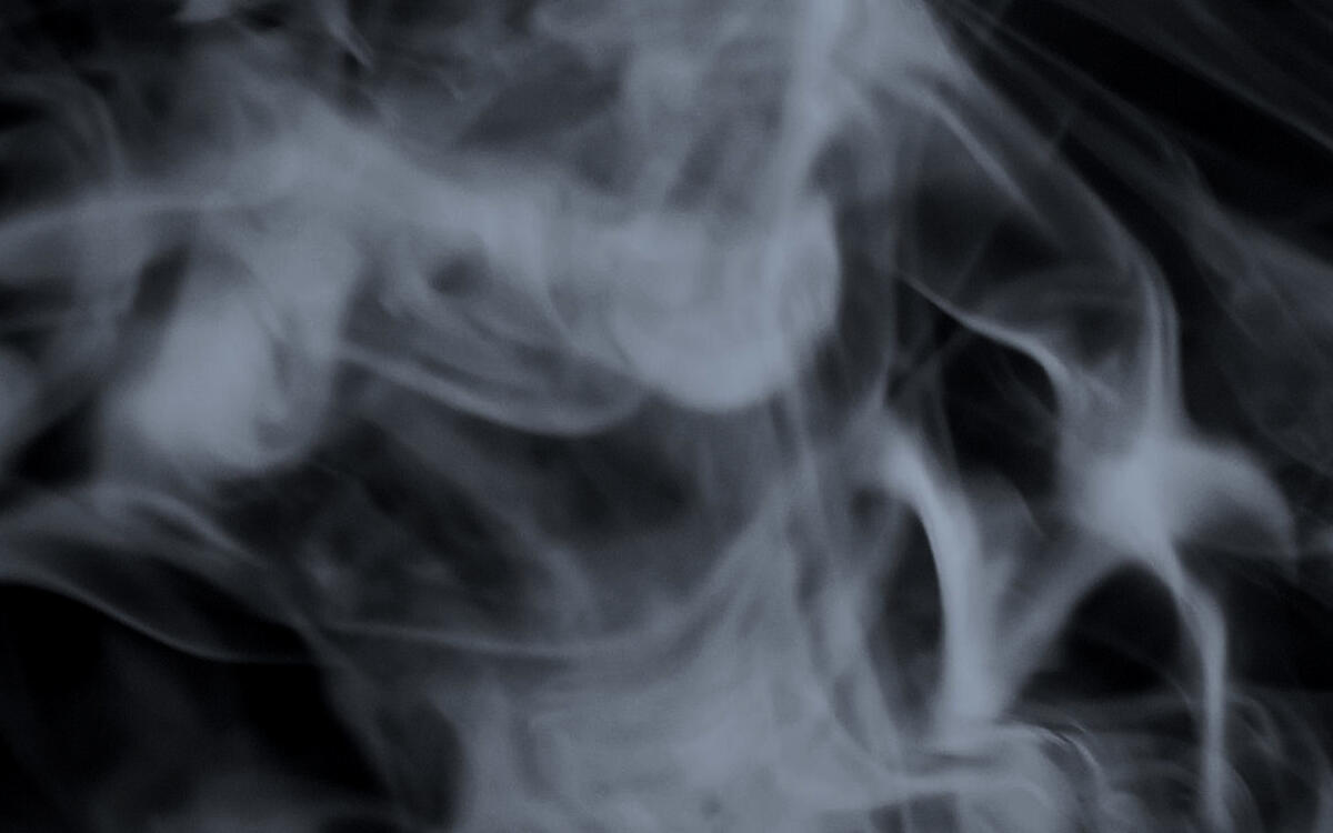 white whispy smoke floats in front of a black background